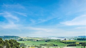 Et panoramaudsigt over et landligt landskab med marker, træer og en by i det fjerne.