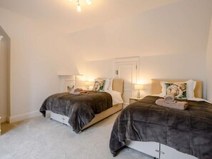 A bedroom with two beds, each with a headboard, bedside tables, and lamps. - 7 Bed in King's Lynn (oc-88492) (Snettisham)