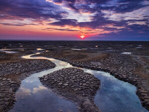 A coastal landscape with a sunset, rocky terrain, and water channels. - 7 Bed in King's Lynn (oc-88492) (Snettisham)