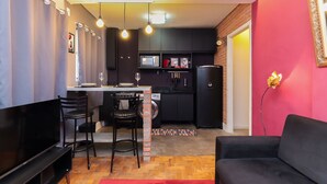 Un espacio habitable compacto con kitchenette, comedor y zona de estar.