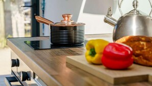 A kitchen counter with a kettle, a pot, and some vegetables.