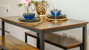 A dining table with blue and gold dinnerware, a vase with flowers, and a wine glass.
