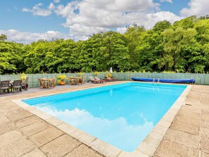 A rectangular swimming pool with a tiled edge, surrounded by a wooden deck.