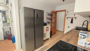 A kitchen with a stainless steel refrigerator, a wooden cabinet, a black stove, and a white tiled backsplash. - La Mata: Beachfront apartment. 2 bedrooms (La Mata)