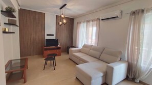 A modern living room with a sofa, TV, and a small table. - La Mata: Beachfront Apartment. 2 bedrooms (La Mata)