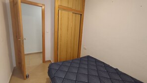 Une pièce avec un lit, une armoire en bois et une porte.