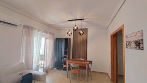A dining area with a table and chairs, a ceiling light fixture, and a view of the outdoors through a window with curtains. - La Mata: Beachfront apartment. 2 bedrooms (La Mata)