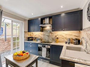 A modern kitchen with dark cabinets, a built-in oven, and a large window. - 2 Bed in Ripon (oc-88051) (Ripon)