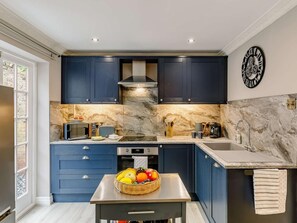 A modern kitchen with dark blue cabinets, a marble backsplash, and a stainless steel sink. - 2 Bed in Ripon (oc-88051) (Ripon)