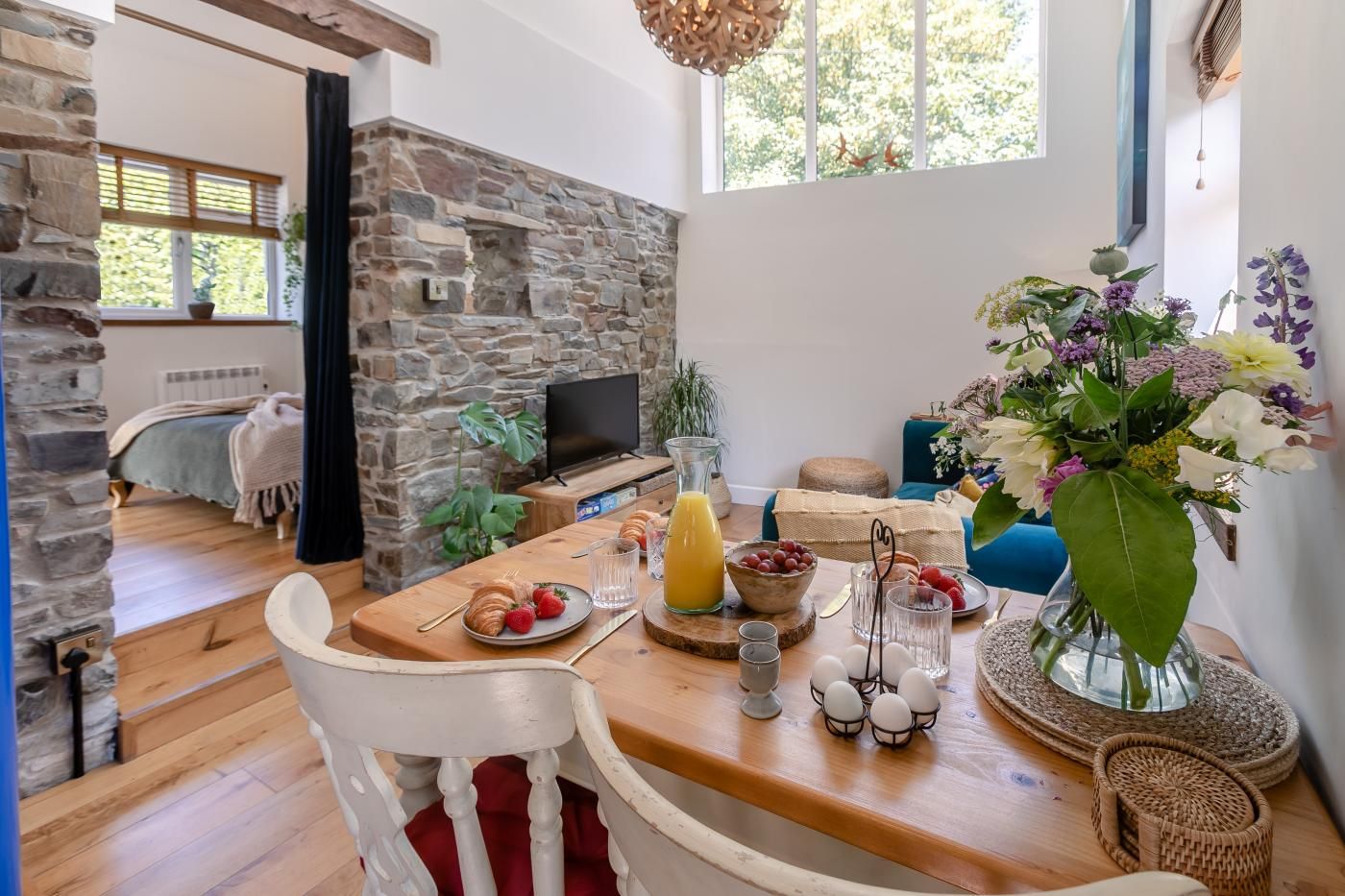 A dining area with a wooden table, chairs, and a variety of food items.