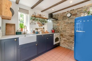 Eine Küche mit dunklen Schränken, einem blauen Kühlschrank, einer Steinwand und einem Fenster mit Blick.