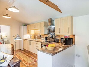 A modern kitchen with wooden cabinets, a granite countertop, and a variety of appliances including a toaster and a kettle.
