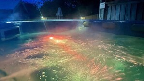Ett bubbelbad med en dimmig atmosfär, omgivet av ett trädäck och ett staket.