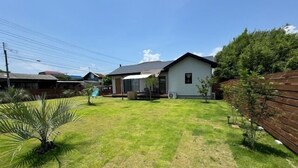 A residential backyard with a house, a wooden fence, and a small tree. - Dog Cottage Surfside Kujukuri (Kujukuri)