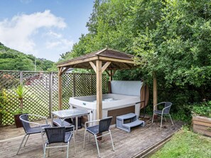 A hot tub under a wooden pergola on a wooden deck with outdoor furniture. - 2 Bed in Saltash (oc-88314) (Notter)