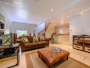 A spacious living room with a leather sofa, a coffee table, and a dining area with a kitchen in the background. - 2 Bed in Ambleside (oc-88319) (Claife)