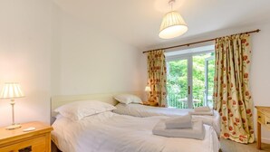 A bedroom with two beds, a bedside table with a lamp, and a window with curtains. - 2 Bed in Ambleside (oc-88319) (Claife)