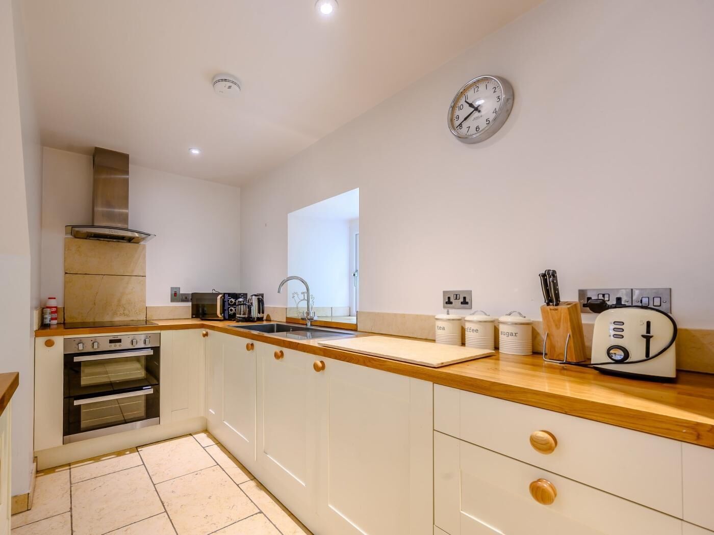 A modern kitchen with a built-in oven, microwave, and stainless steel range hood.