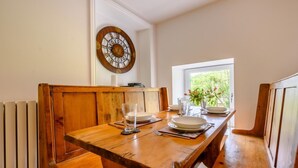A wooden dining table with benches, a wall clock, and a window with a view of greenery. - 2 Bed in Ambleside (oc-88319) (Claife)