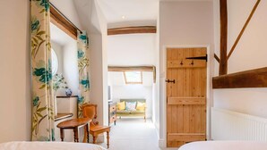 A bedroom with two beds, a wooden door, a mirror, a small table, and a chair. - 4 Bed in Buxton (oc-88196) (Hartington)