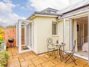 Eine Terrasse mit Grill, einem Tisch und Stühlen sowie einer Glastür zum Schlafzimmer.