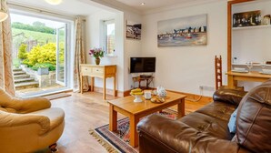 A living room with a sofa, a coffee table, a TV, and a painting on the wall. - 1 Bed in Totnes (oc-88098) (North Huish)