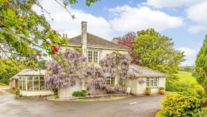 A house with a covered porch, a chimney, and a garden with various plants. - 1 Bed in Totnes (oc-88098) (North Huish)
