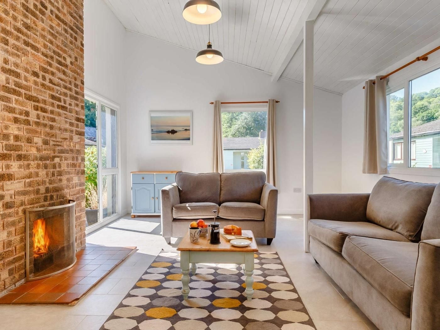A cozy living room with a fireplace, a sofa, a coffee table, and a view of the outdoors.
