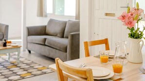A dining area with a table set for two, a vase with flowers, and a pitcher of orange juice. - 2 Bed in Saltash (oc-88309) (Notter)