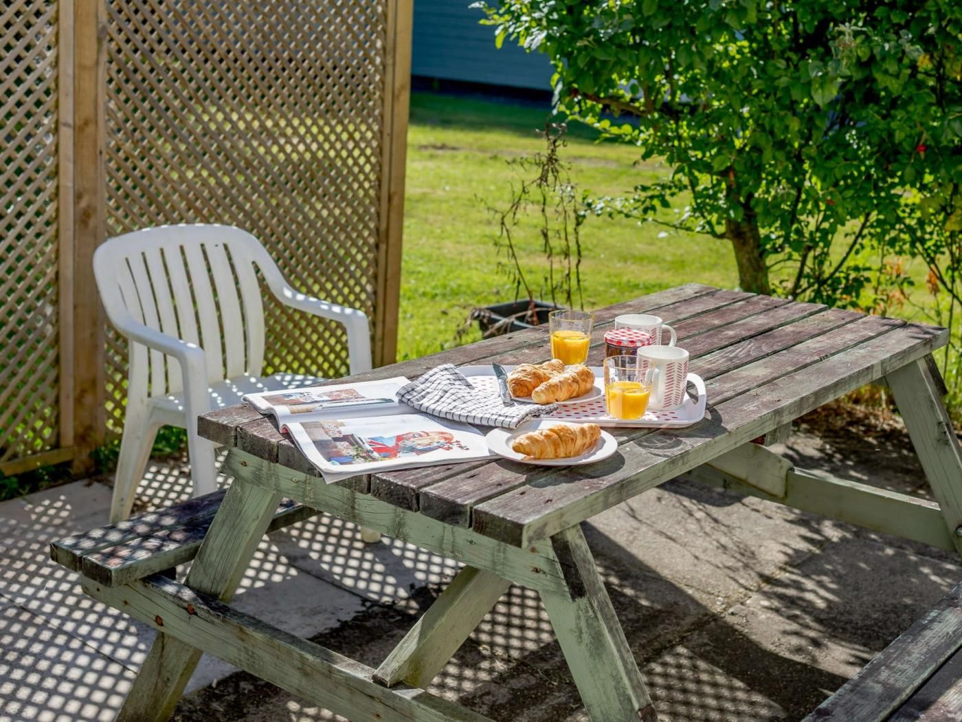 Ein Holztisch für ein Picknick mit einer Zeitung, Croissants und Orangensaft.