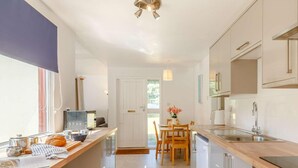 A modern kitchen with a wooden countertop, stainless steel appliances, and a dining area with a table and chairs. - 2 Bed in Saltash (oc-88309) (Notter)