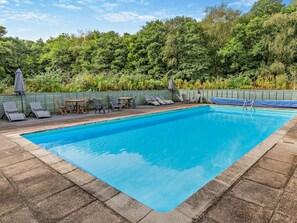 En rektangulär swimmingpool med ett klart, blått vatten och en omgivande terrass av sten.