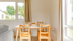 A dining area with a table set for two, a bowl of fruit, and a view of the outside. - 2 Bed in Saltash (oc-88311) (Notter)