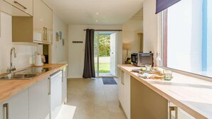 A modern kitchen with a sink, stove, and dining area with a window. - 2 Bed in Saltash (oc-88311) (Notter)