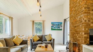 A living room with a sofa, a coffee table, a fireplace, and a painting on the wall. - 2 Bed in Saltash (oc-88311) (Notter)
