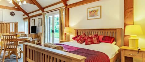 A bedroom with a wooden bed, a wooden headboard, a bedside table with a lamp, and a window with curtains.