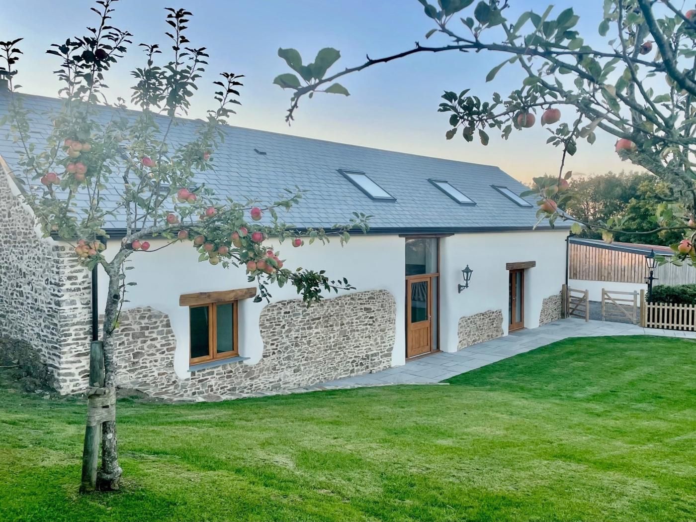 A stone house with a sloped roof, a small porch, and a well-maintained lawn.