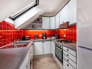 Et moderne køkken med hvide skabe, en gasblus og en backsplash med røde fliser.