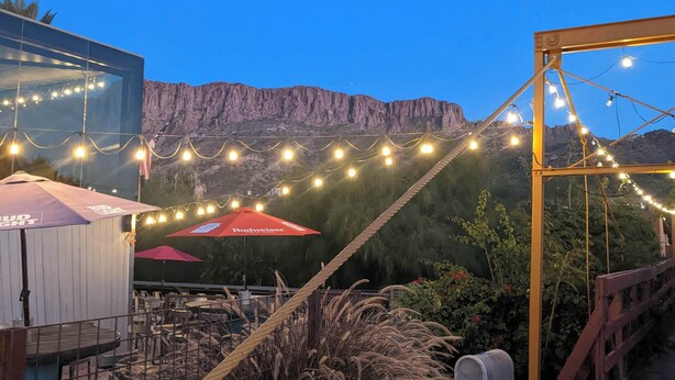 A rustic outdoor seating area with string lights, a red umbrella, and a mountain backdrop. - Dog Friendly home walking distance to downtown (Superior)