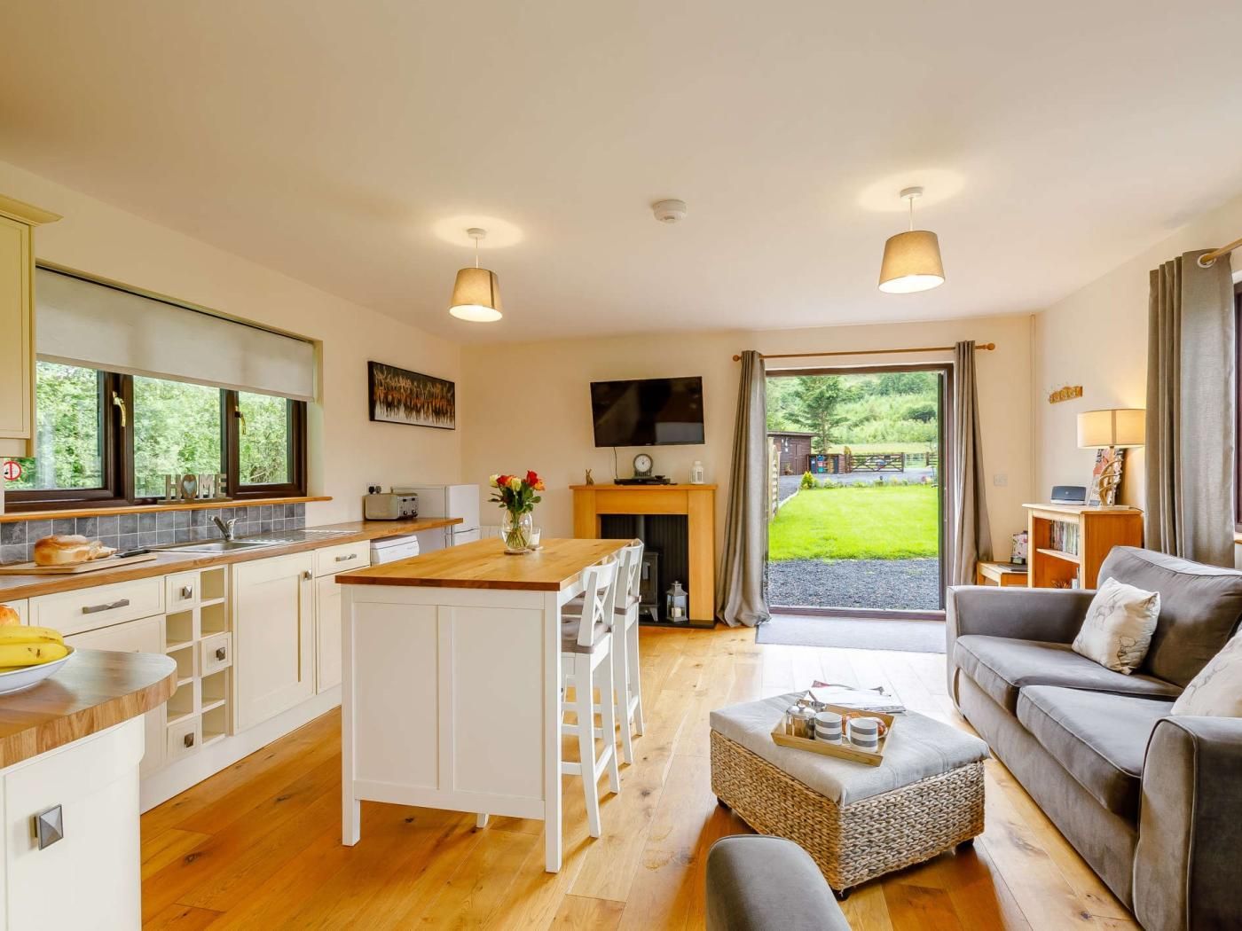 A modern kitchen with a central island, a dining area with a sofa, and a living room with a fireplace.