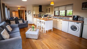 Una cocina moderna con una isla central, un área de comedor con sofá y un cuarto de lavandería.
