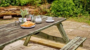 A picnic table with a croissant, a cup, a pitcher, and a small plant. - 2 Bed in Saltash (oc-88310) (Notter)