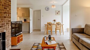 A living room with a sofa, a coffee table, a TV, and a fireplace. - 2 Bed in Saltash (oc-88310) (Notter)