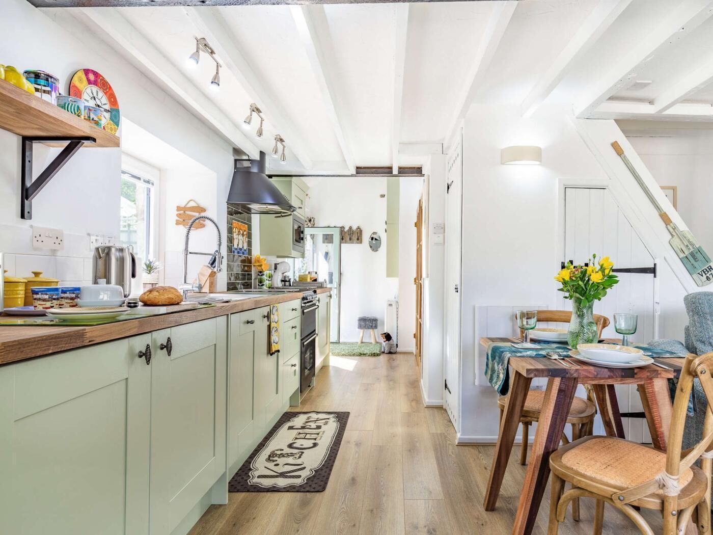 Una cocina con encimera de madera, extractor de aire negro y zona de comedor con mesa y sillas.