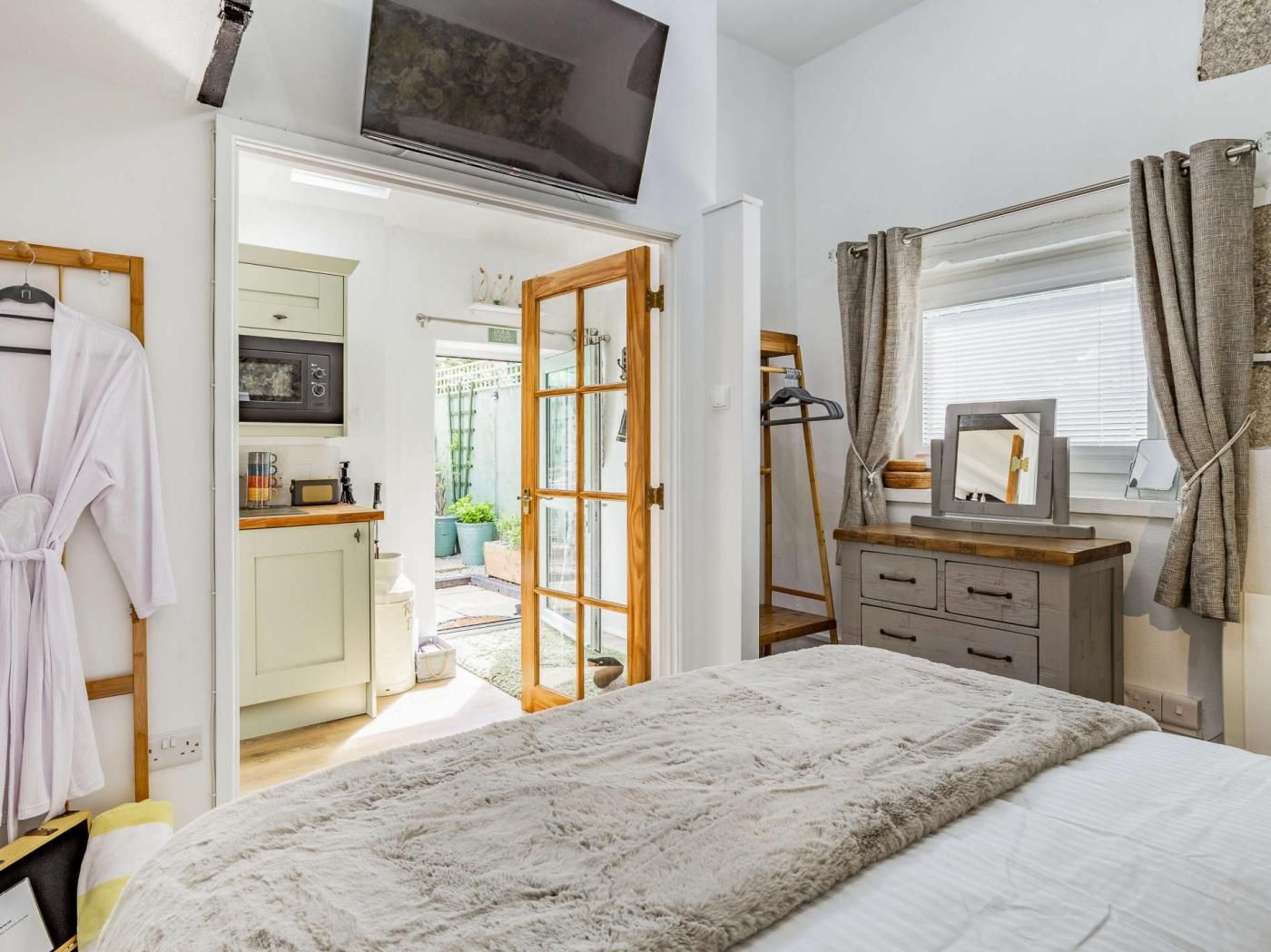 A bedroom with a bed, a television, a wardrobe, and a bathroom visible through an open door.