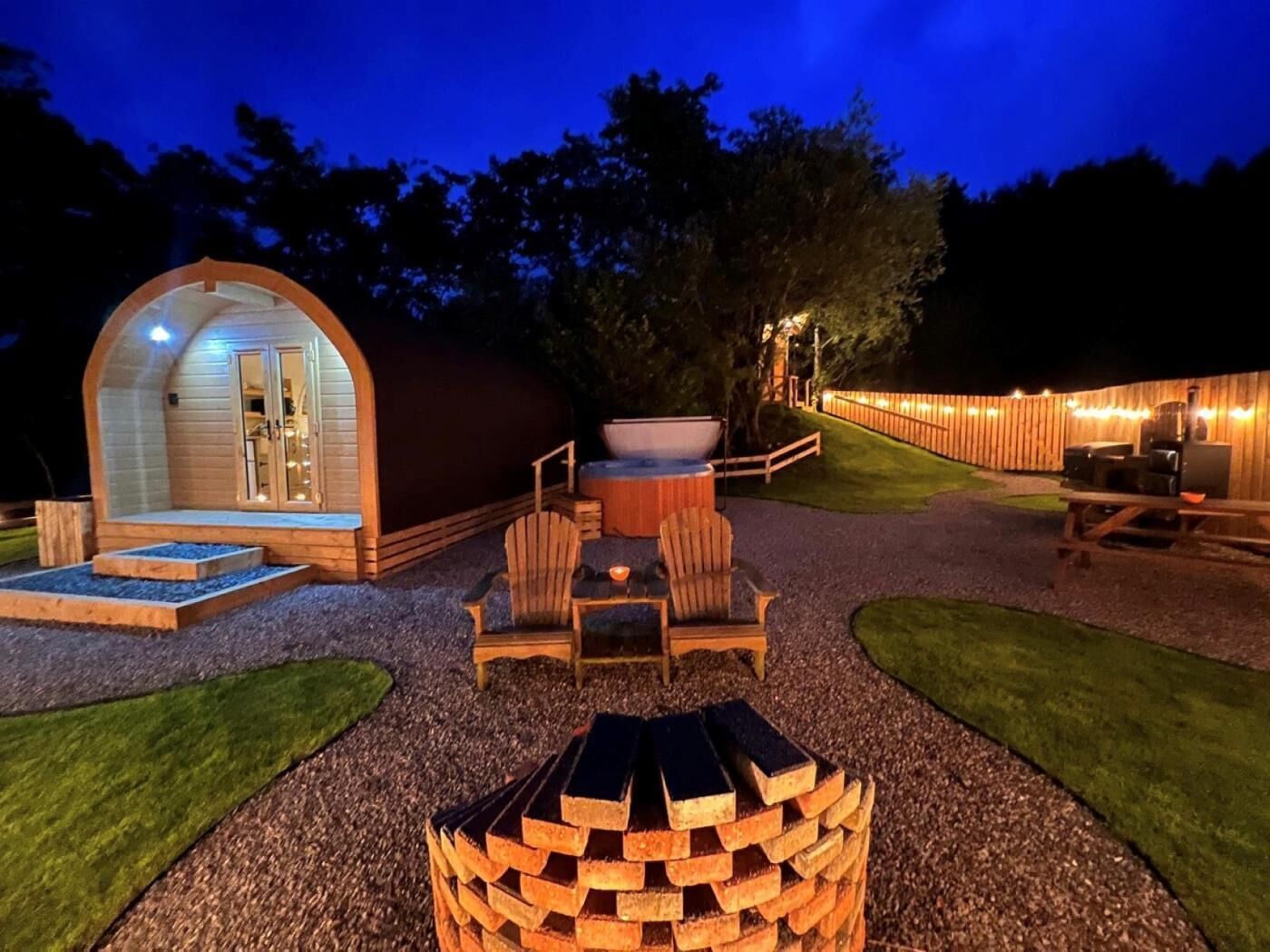 A cozy outdoor area with a wooden structure, seating, and a hot tub.