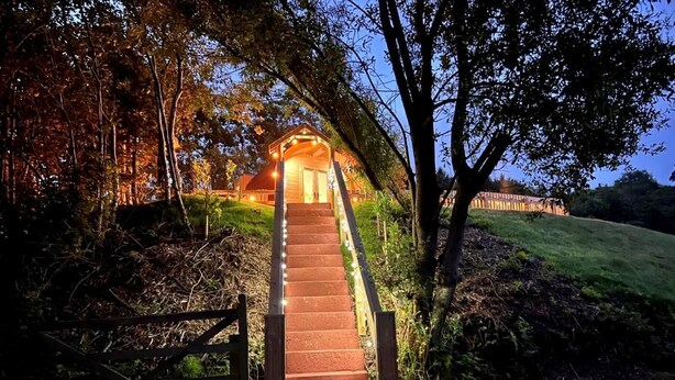 A staircase leading to a building with a porch, surrounded by trees and a gate.