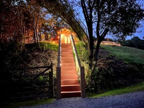 Un escalier menant à un bâtiment doté d’un porche, entouré d’arbres et d’une grille.