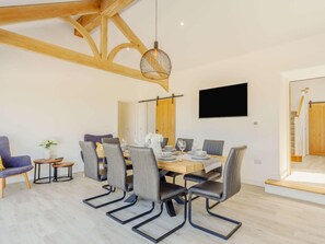 A modern dining area with a wooden ceiling, a round hanging light fixture, and a flat-screen TV mounted on the wall. - 3 Bed in Redruth (oc-88102) (Redruth)