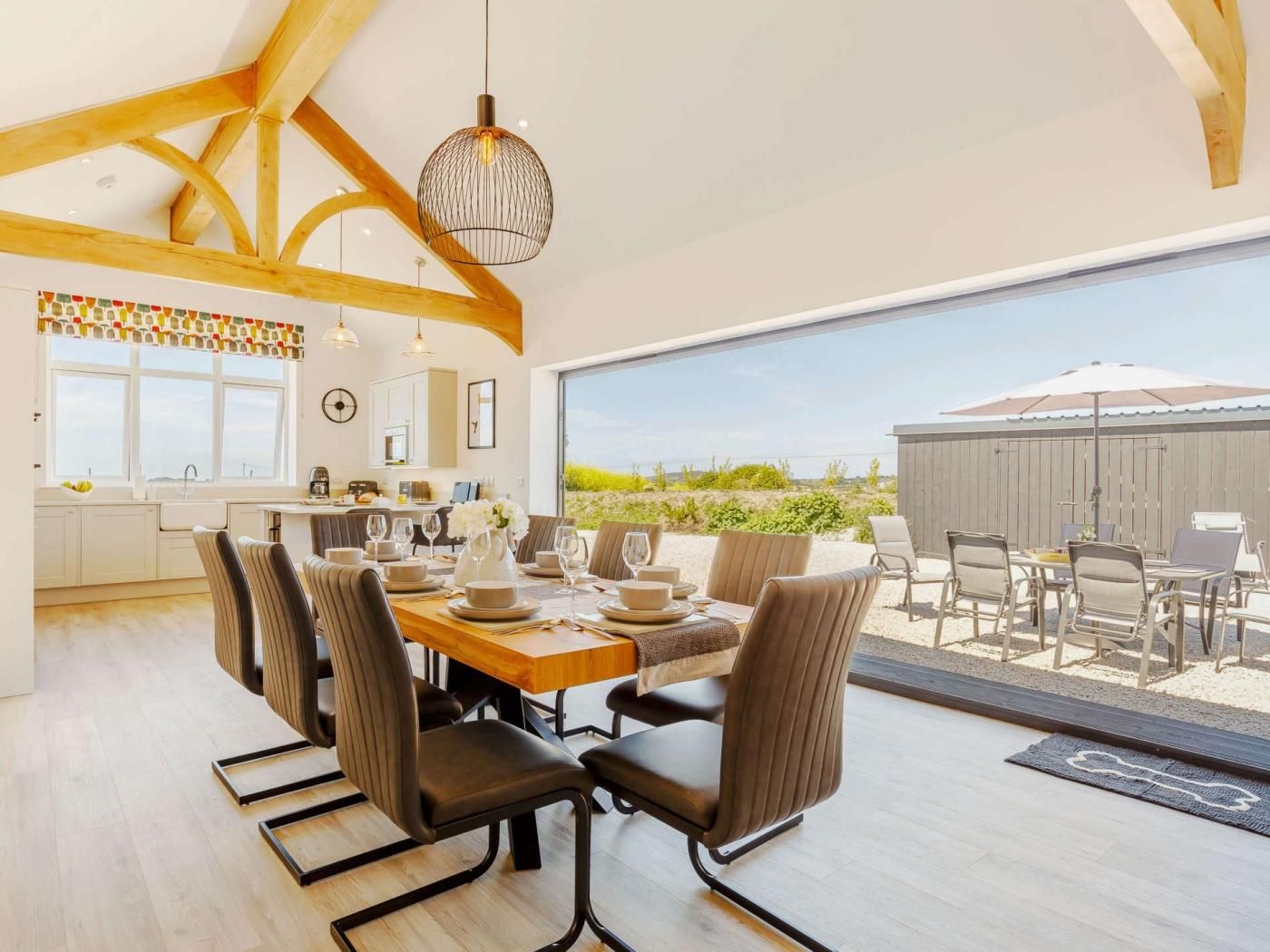 A spacious dining area with a large table set for six, surrounded by chairs, and a view of the outdoors.